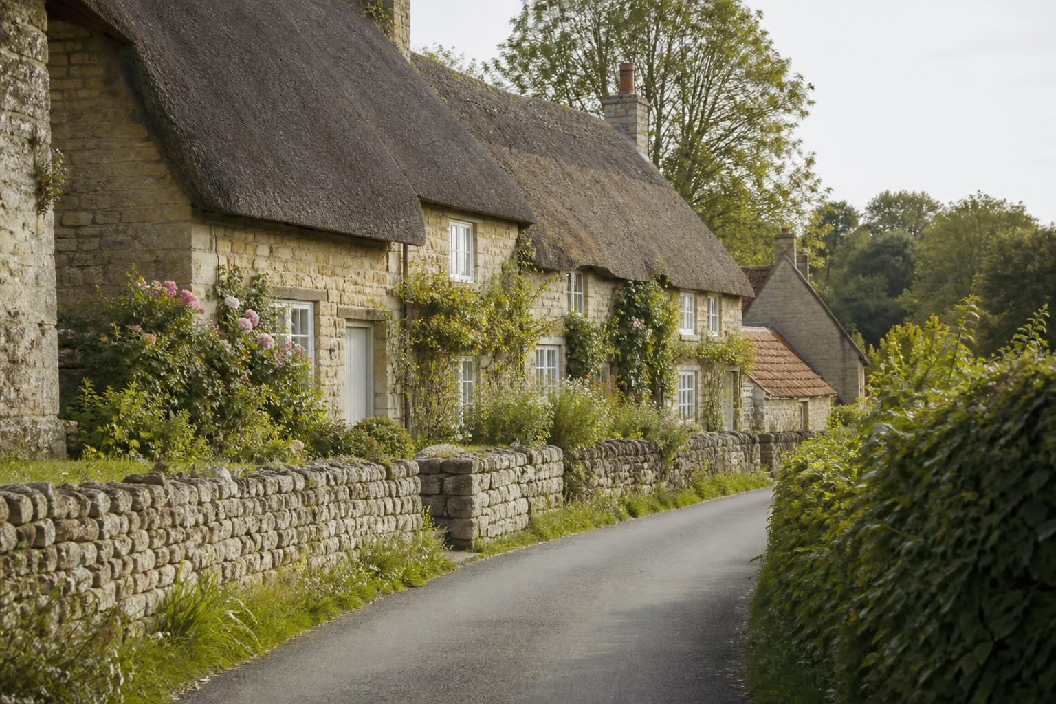 A quiet English village lane with thatched cottages and roses