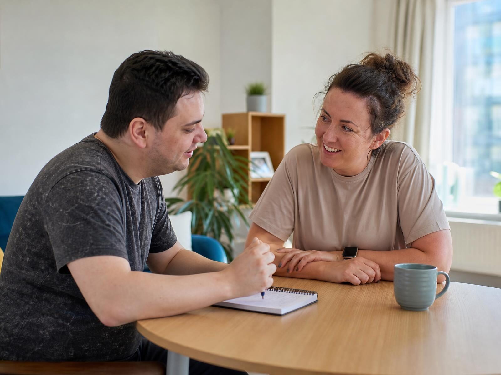 A support worker and a working-age adult planning weekly activities together in a supported living apartment